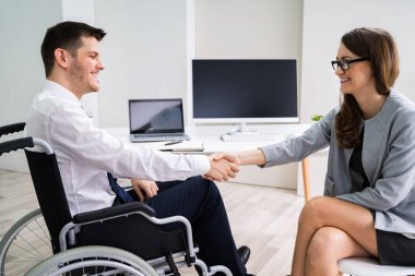 İş kadını ofiste onun meslektaşı ile el sıkışan tekerlekli sandalyede