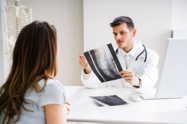 Doktor, hastayla ayak röntgeni hakkında konuşuyor.