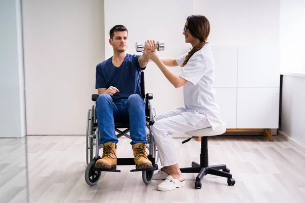 Terapeuta Que Ayuda Paciente Masculino Mientras Hace Ejercicio Con Dumbbell — Foto de Stock