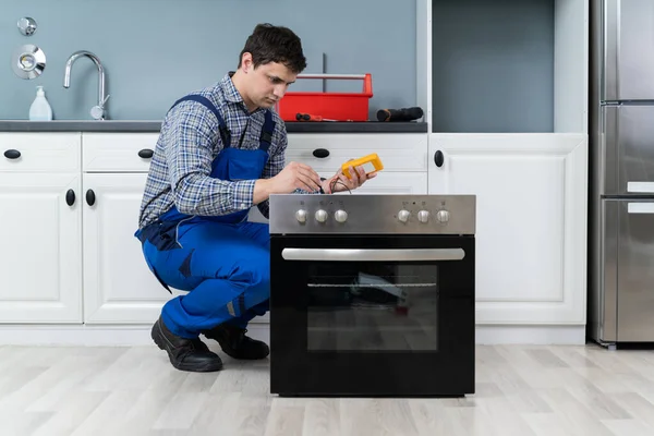 Joven Técnico Chequeando Horno Con Multímetro Digital — Foto de Stock