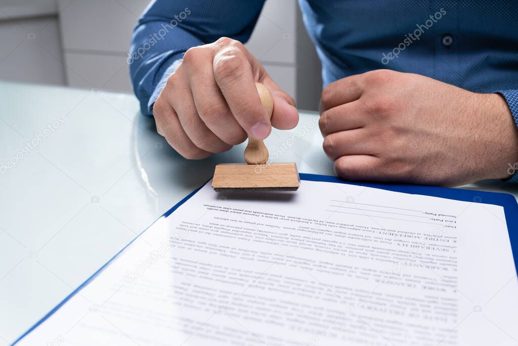 Close-up Of Businessman Hand Using Stamper On Document