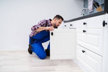 Genç tamirciyle mutfakta lavabonun kapı sabitleme