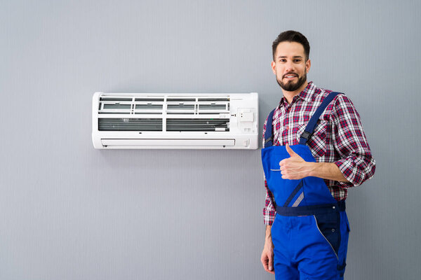 Happy Male Technician Gesturing Thumb Up Near Air Conditioner