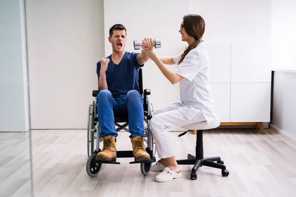 治疗师在使用哑铃运动时协助快乐男性病人 — 图库照片