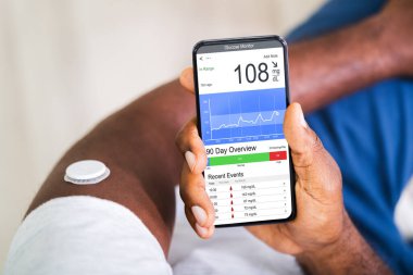 Ekranda kötü kan şekeri seviyesiyle elinde akıllı telefon tutan adam.