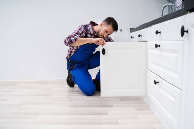 Genç tamirciyle mutfakta lavabonun kapı sabitleme