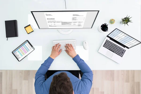 オフィスのコンピュータで請求書を確認するビジネスマンの高い角度ビュー — ストック写真