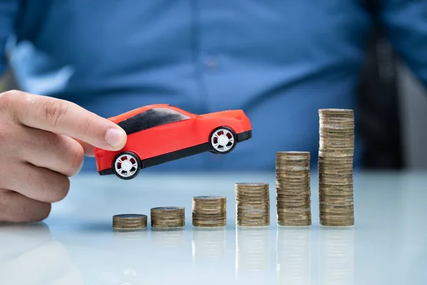 Persona Sosteniendo Coche Rojo Sobre Aumento Monedas Apiladas — Foto de Stock