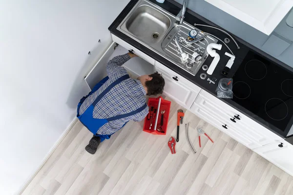 Trabajador Acostado Piso Reparación Fregadero Cocina Con Llave Ajustable —  Fotos de Stock