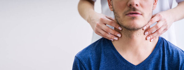 Close-up Of A Doctor's Hand Touching The Throat Of A Male Patient In The Clinic