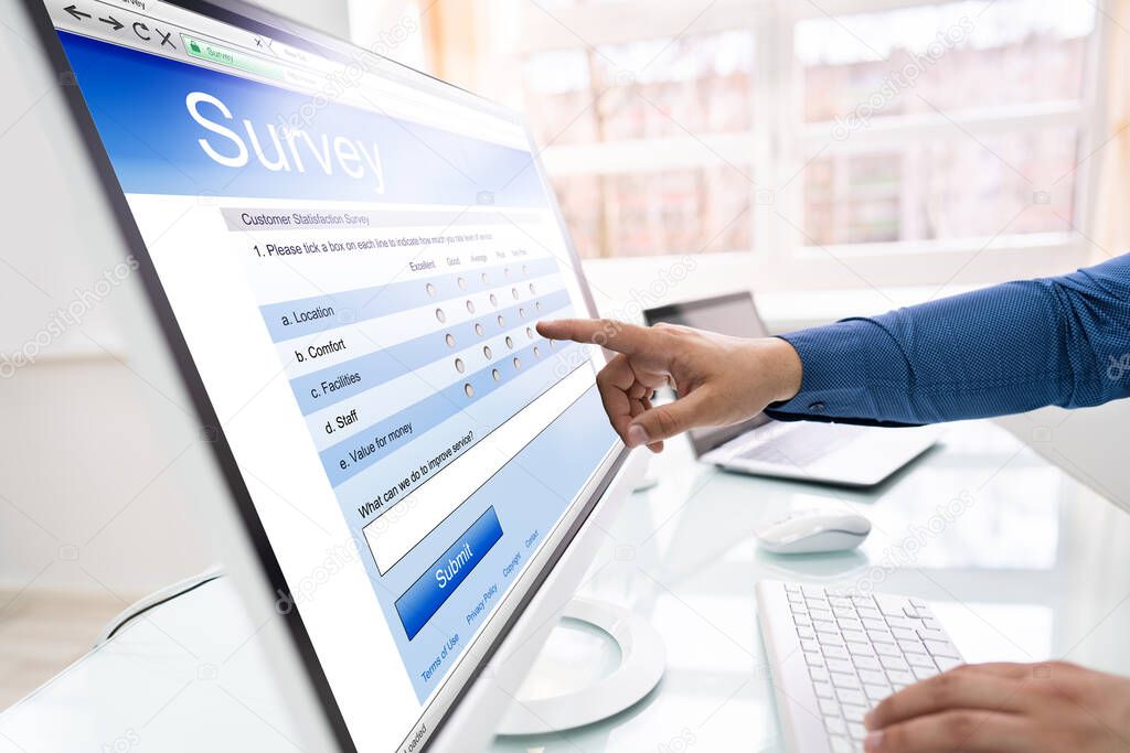 Close-up Of A Businessperson's Hand Filling Online Survey Form On Computer In Office