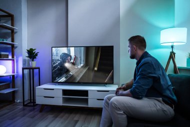 Evde televizyon izlerken kanepede yatan adam