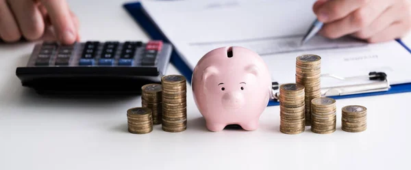 Geschäftsmann Mit Taschenrechner Mit Gestapelten Münzen Und Sparschwein Auf Holztisch — Stockfoto