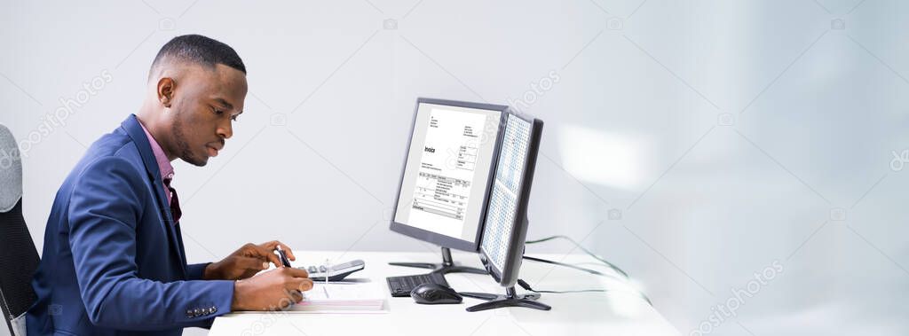 Side View Of A Businessman Checking Invoice On Computer At Workplace