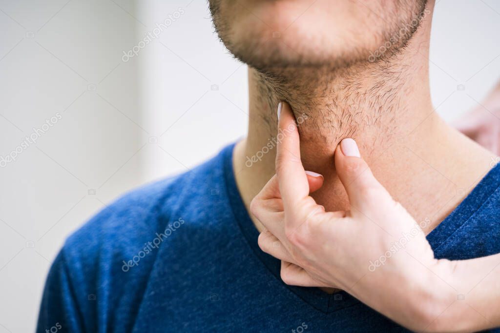 Close-up Of A Doctor's Hand Touching The Throat Of A Male Patient In The Clinic