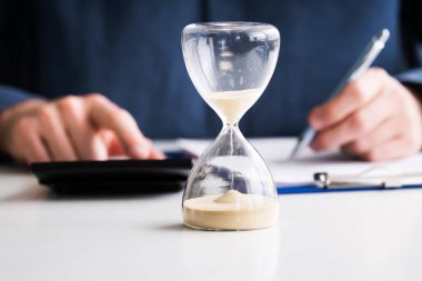 Kum saati fatura hesaplama işadamının'ın el önünde Close-Up