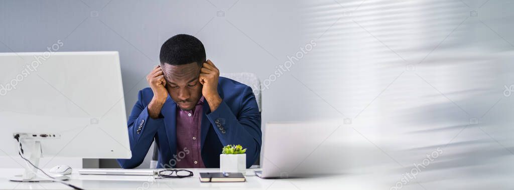 Worried Young Businessman Looking At Computer At Office Desk