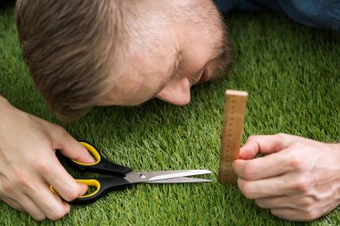 Close-up Of A Man Cutting Green Grass Measured With Ruler clipart