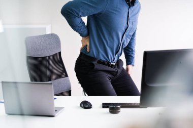 Ofis masasının yanında duran Sırtı Aşağı Ache ile İşadamı