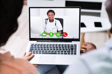 Evde bilgisayarında doktorla görüntülü konuşma yapan bir çift.