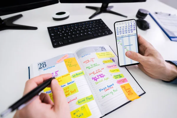 Крупный План Бизнесмена Держащего Расписание Написания Сотовых Телефонов Дневнике Ручкой — стоковое фото