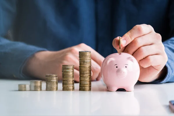 Personens Hand Infoga Mynt Piggybank Med Ökande Mynt Stack Skrivbord — Stockfoto