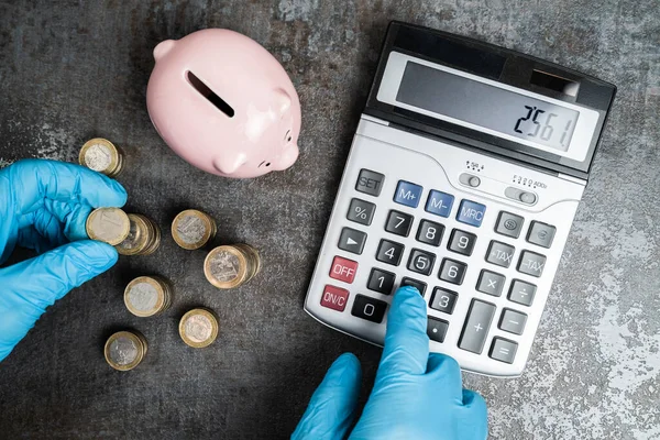 Accountant In Gloves Calculating Piggybank Money Budget During Coronavirus Pandemic