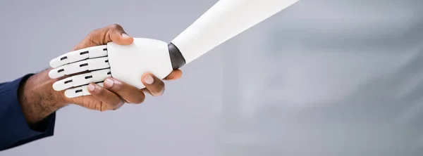 商人与机器人在灰色背景下握手的特写 — 图库照片
