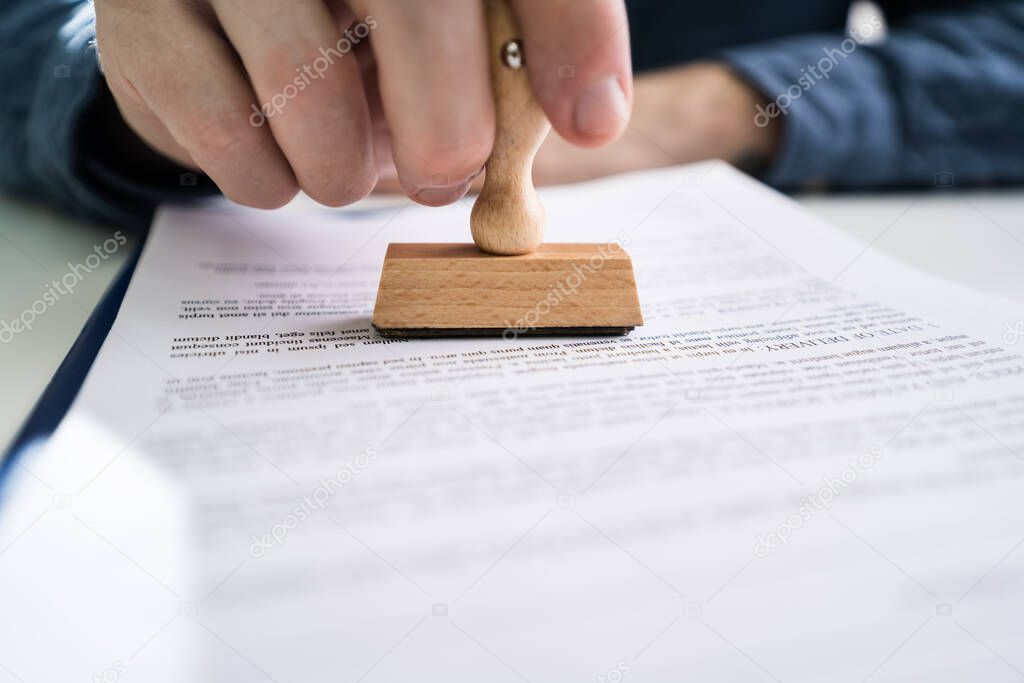 Close-up Of Person Hands Using Stamper On Document With The Text Approved