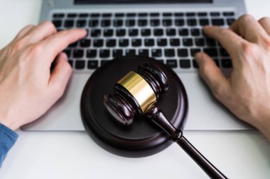 Bir iş adamının elinin, Gavel masadayken dizüstü bilgisayarını kullanırken yakın plan fotoğrafı.