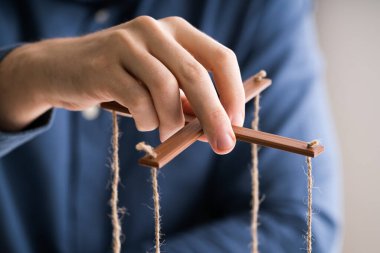 Gri arka planda iple Marionette 'i manipüle eden Bir Kişi' nin Yakın Çekimi