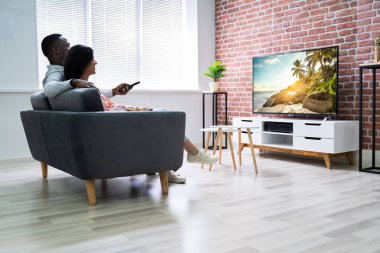 Evde TV 'de film izleyen bir çiftin arka görüntüsü.
