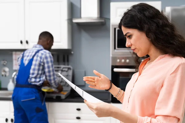 Young Frustrated Woman Looking Expensive Bill Clipboard Plumber Standing Kitchen — Stock Photo, Image