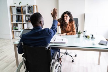 Engelli İşadamı, gülümseyen kadın ortağına beşlik çakıyor.