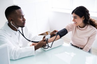 Hastaların kan basıncını steteskopla ölçen doktorun yakın çekimi.