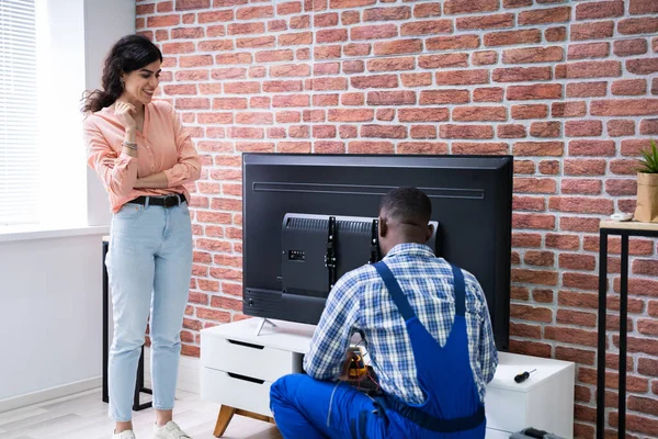 Jeune Femme Assise Sur Canapé Regardant Technicien Masculin Réparer Télévision — Photo