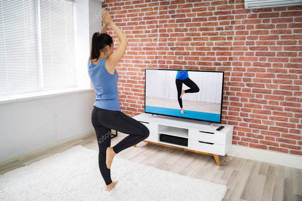 Fit Woman Doing Online Fitness Yoga Workout Near Television