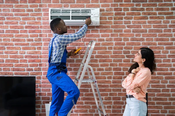 Young Woman Looking Male Technician Repairing Air Conditioner Mounted Brick — Stock Photo, Image