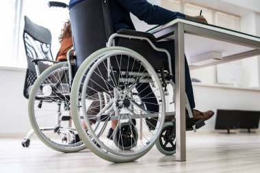 Ofiste tekerlekli sandalyede oturan engelli iş kadını