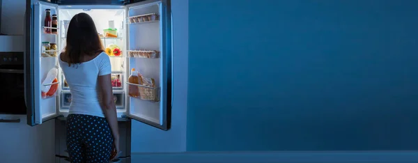 空腹の人は夜に冷蔵庫から食べ物を食べる — ストック写真
