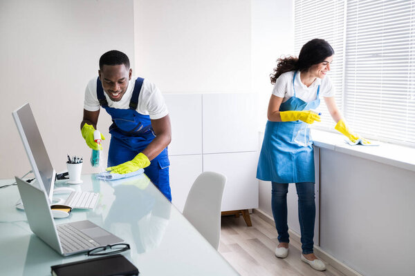 Young Male And Female Cleaners Cleaning Office