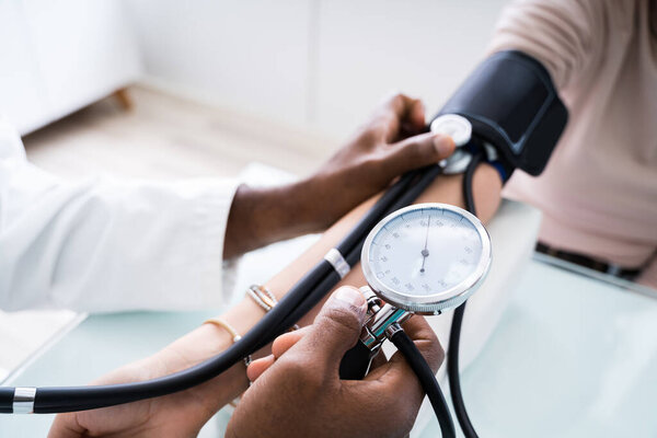 Close-up Of Doctor Measuring Patients Blood Pressure With Stethoscope