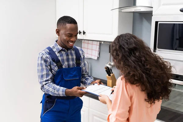 Glimlachende Klant Vrouw Ondertekenen Appliance Repair Factuur Voorkant Van Loodgieter — Stockfoto