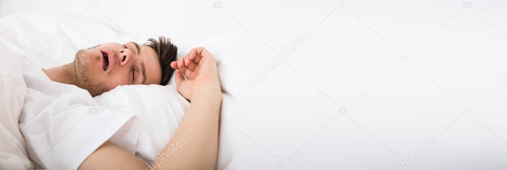 View Of Tired Young Man Snoring While Deep Sleeping In Bed