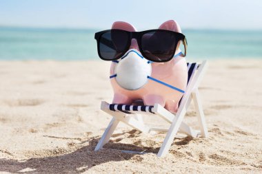 Seyahat sigortası. Kumsaldaki Domuz Kumbarası Yüz Maskesi