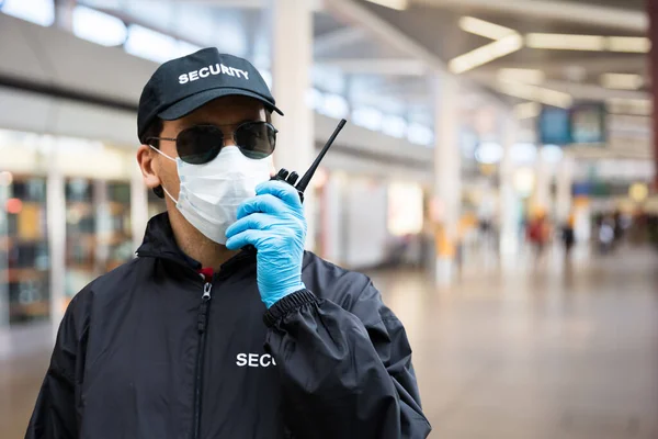 Security Guard Standing In Face Mask In Airport Terminal