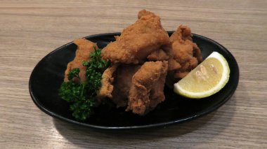 Kara-yaş-Japon çıtır kızarmış tavuk dilimlenmiş limon siyah plaka üzerinde