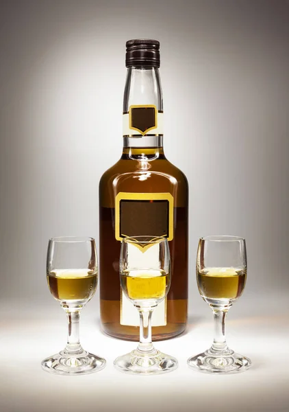 Láhev a tři sklenice na lihoviny — Stock fotografie