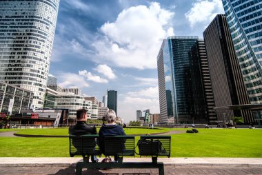 Paris, Fransa - 3 Mayıs 2011: Paris, Fransa'da modern binalar ile La Defense bölgesinde bankta oturan çift. La Defense olduğu Paris büyük iş bölgesinde.