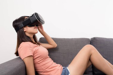 Kanepede oturan ve Vr aygıtla ile ilgilenen kadın